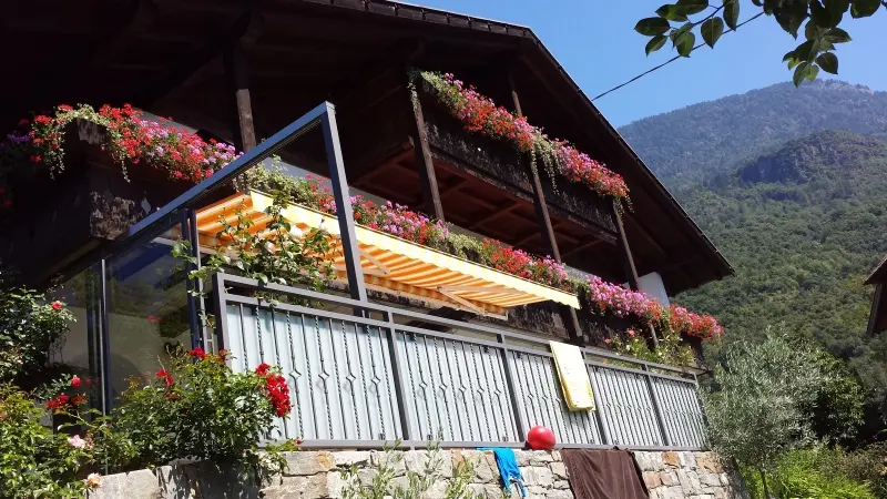 Geländer an einer Terrasse eines klassisch oberbayerischen Hauses, das mit Geranien geschmückt ist