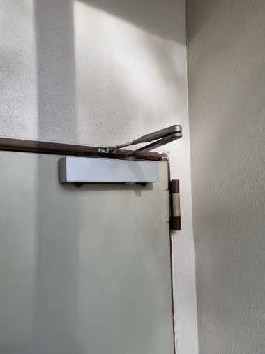 Kleinreparaturen für Hausverwaltungen Oberschließer an einer Tür wird repariert