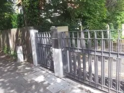 Metallzaun und Tor bei einer gepflasterten Hauszufahrt